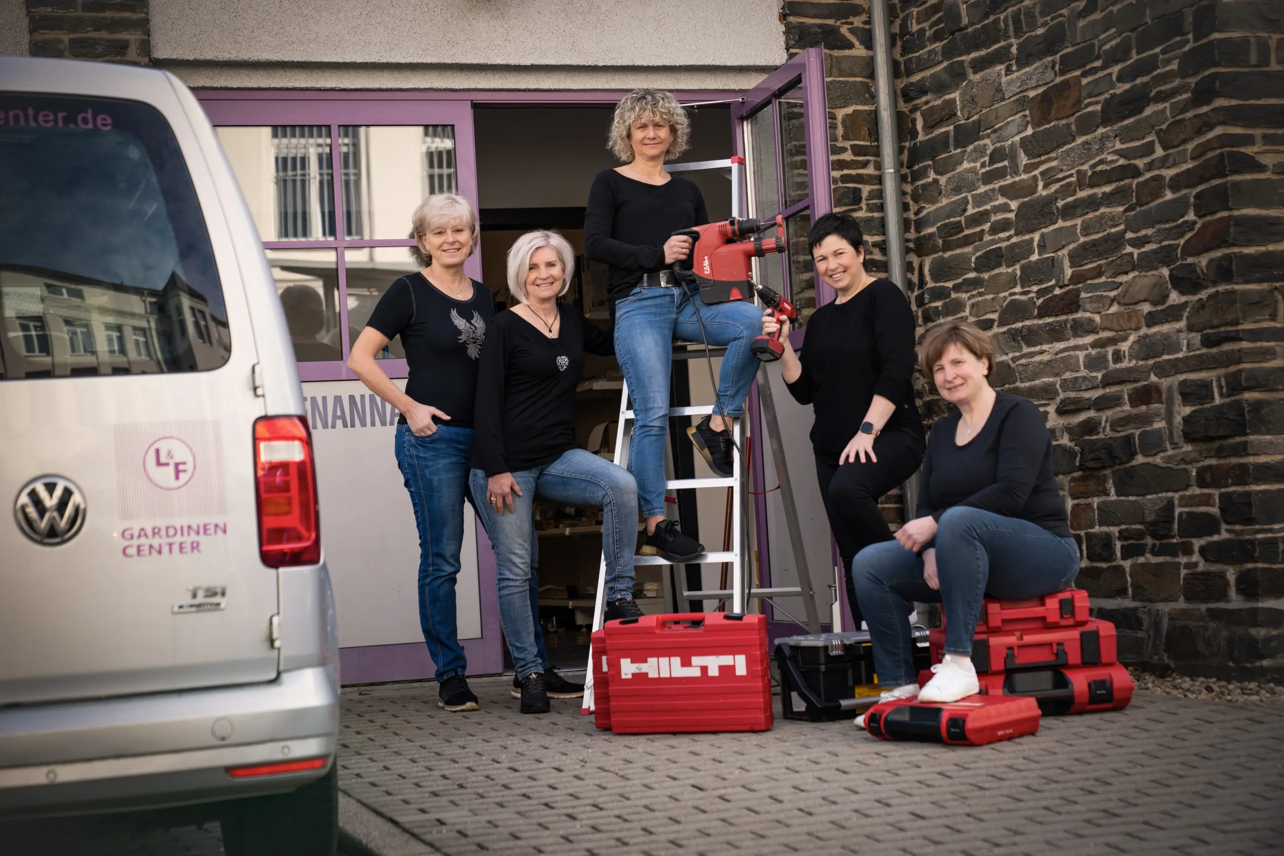 Unsere Montage-Mitarbeiterinnen mit Leiter und Werkzeug vor unserem Firmengebäude.